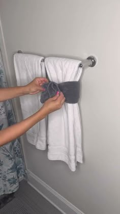 a woman is drying her hands on a towel rack in the bathroom with towels hanging from it