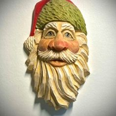 a close up of a santa claus mask on a white wall with a red hat