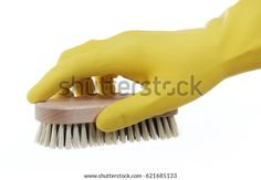 a hand in yellow rubber gloves holding a brush