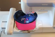 a baseball cap is sitting on top of a sewing machine with a pink and blue hat