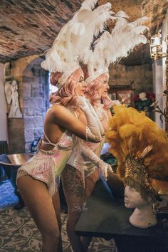 two women dressed up in costumes and headgear, one is holding onto a mannequin