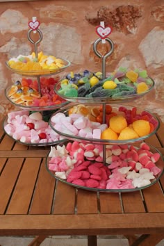 three tiered trays filled with different types of candies on top of a wooden table