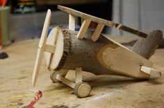 a wooden toy airplane sitting on top of a table next to a piece of wood