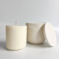 two white candles sitting next to each other