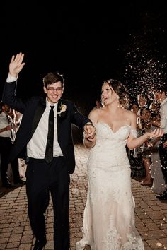 a bride and groom walk through confetti thrown by guests at their wedding reception