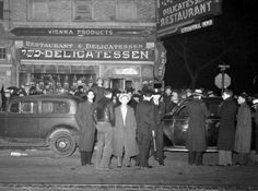 an old black and white photo of people standing in front of a restaurant at night