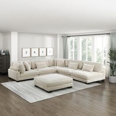 a living room filled with furniture and a large white ottoman on top of a hard wood floor