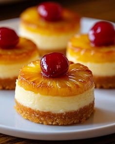 three small desserts on a white plate topped with cherries and pineapple slices