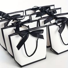 six black and white gift bags with bows on the front, tied in satin ribbon