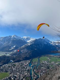 a person paragliding over a city with mountains in the background