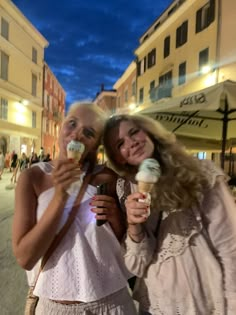 two women standing next to each other eating ice cream