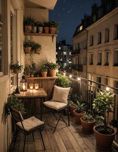 a balcony with potted plants and candles lit up at night on the outside deck