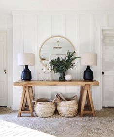 a wooden table with two baskets underneath it and a mirror on the wall behind it