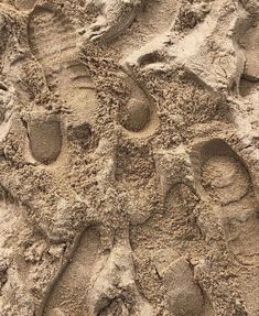 footprints in the sand with one person's feet sticking out from behind them,