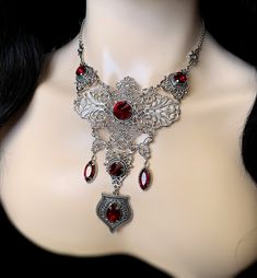 "This elegantly ornate necklace is made with light weight, antique silver tone filigrees and pendants, featuring romantic scrolls and beautifully balanced details. Its mesmerizing design is accented with dazzling dark ruby red glass crystals/jewels. Decorated portion is 6 1/2\" wide and 4 3/4\" tall in the very center. Necklace length is adjustable 15\"-18\" with soldered stainless steel cable chain, lobster clasp and extender. If you would like a different length, please send us a message. Matc Red Metal Filigree Jewelry, Antique Silver Filigree Metal Necklace, Gothic Metal Necklace With Intricate Design, Ornate Filigree Silver Bridal Necklace, Wedding Filigree Metal Necklaces, Ornate Silver Bridal Necklace, Gothic Filigree Necklace For Wedding, Gothic Wedding Necklace With Filigree Detail, Gothic Filigree Wedding Necklace