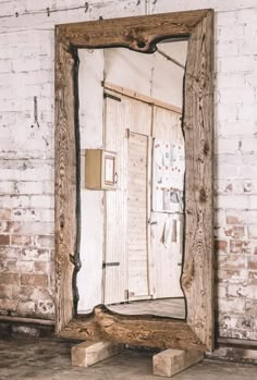 an old mirror sitting on the floor in front of a brick wall with peeling paint