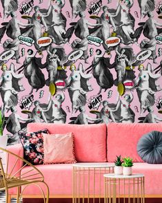 a pink couch sitting in front of a wall with cartoon cats on it's face