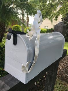 a white mailbox with a metal lizard on it's front and the letter g