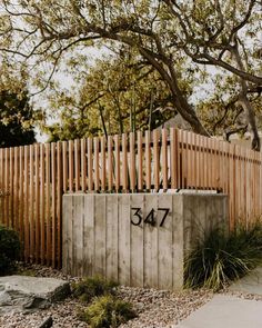 a wooden fence with the number 547 written on it in front of a tree