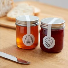 two jars filled with jam sitting on top of a wooden table