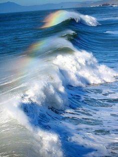 two rainbows in the sky over an ocean wave