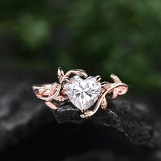 an engagement ring with a heart shaped diamond in the center on top of a rock