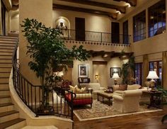 a living room filled with lots of furniture and a staircase leading up to the second floor