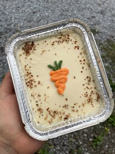 a person holding up a tin tray with food in it and carrots on top