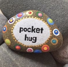 a rock with the words pocket hug painted on it sitting on top of some rocks