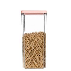 a glass container filled with yellow peas on a white background and a pink lid over the top