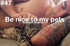 a man laying on top of a bed next to a cat with tattoos on his arm