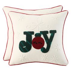 two white pillows with red trimmings and joy embroidered on the front one has a christmas ornament