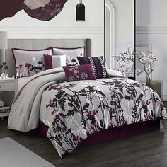 a bed with purple and white comforters in a room