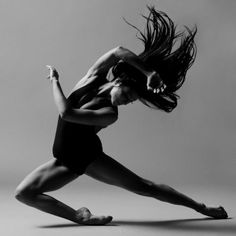 black and white photograph of a woman doing a dance pose with her hair blowing in the wind