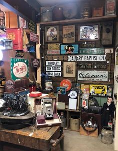 a room filled with lots of old signs and other things on the wall next to a table