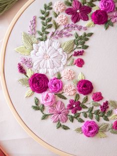 a close up of a embroidery on a hoop with flowers and leaves in the center