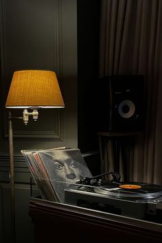 an old record player sitting on top of a table next to a lampshade