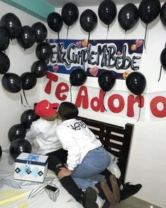 a woman sitting on top of a wooden bench next to black balloons hanging from the ceiling