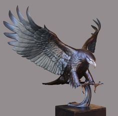 a statue of an eagle with its wings spread and talons down, on a wooden base