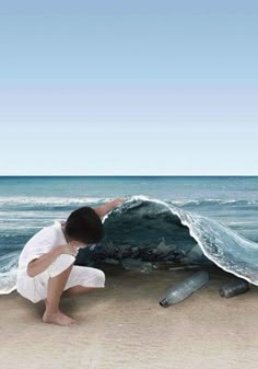 a man kneeling down next to a rock on the beach near an ocean with waves coming in