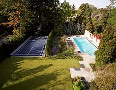 an aerial view of a backyard with a tennis court and swimming pool in the foreground