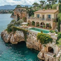 an aerial view of a house with a pool and cliffs in the foreground, surrounded by greenery