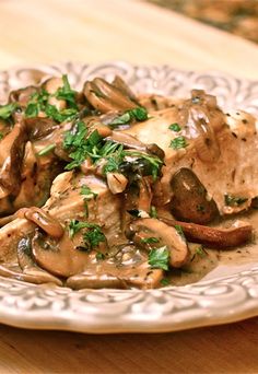 a white plate topped with mushrooms and gravy on top of a wooden table