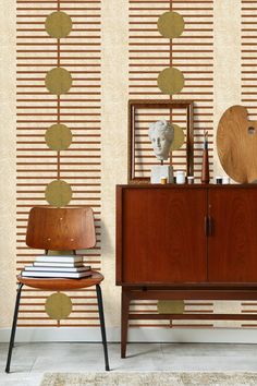 a wooden cabinet sitting in front of a wallpapered wall with circles and lines on it