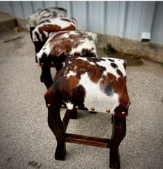 three brown and white cow hide stools