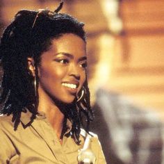 a woman with dreadlocks on her head holding a microphone and smiling at the camera