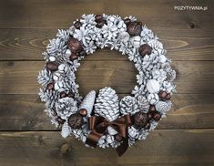 a christmas wreath with pine cones and other decorations on a wooden surface, ready to be hung