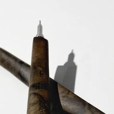 the shadow of a person standing on top of a tall metal pole in front of a white wall