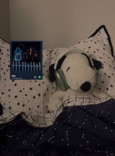 a stuffed dog with headphones laying on top of a bed next to an mp3 player