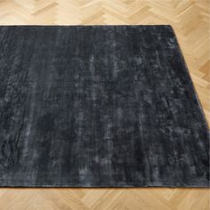 a black area rug on a wooden floor with parquet floors in the foreground